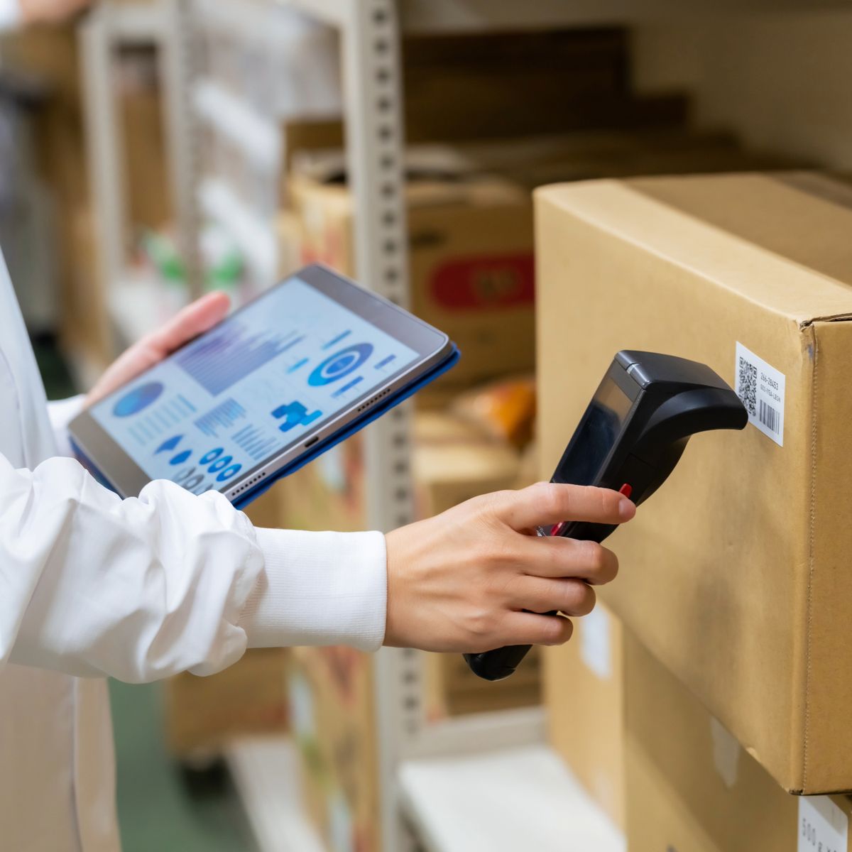ハンディ端末で荷物のバーコードを読み取りながら、タブレットで状況を確認する手元